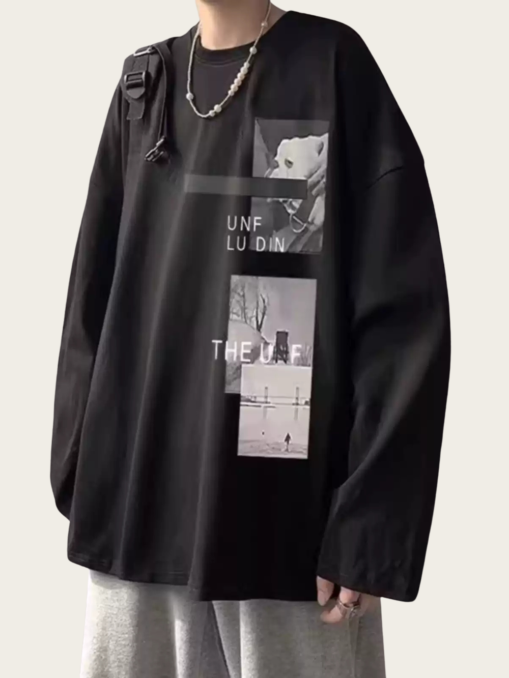 Person wearing a black oversized sweatshirt with graphic designs on a plain background