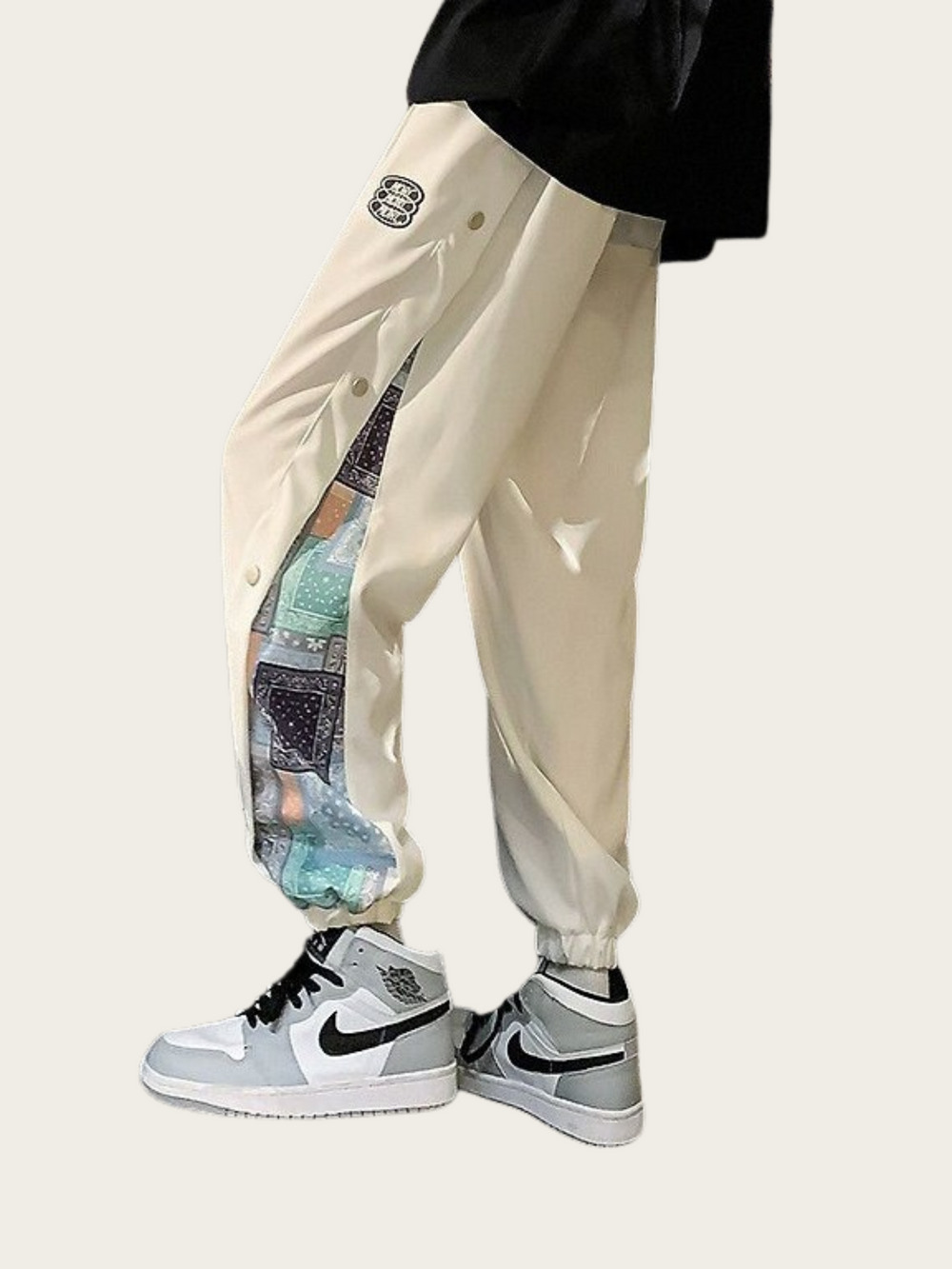 Beige pants with a colorful inner lining worn by a person, paired with gray sneakers on a white background.
