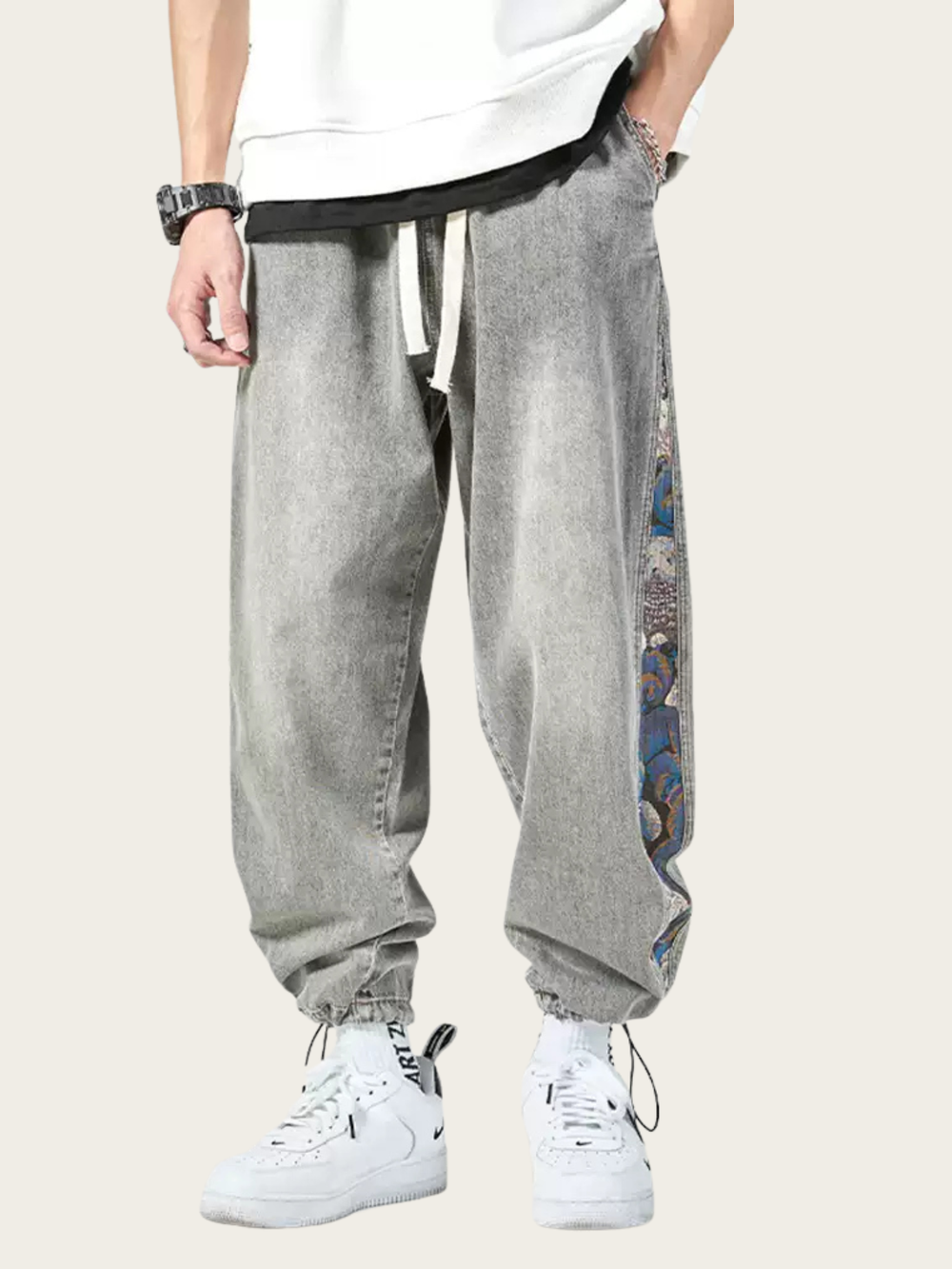 Person wearing gray baggy pants with colorful patterns on a plain background
