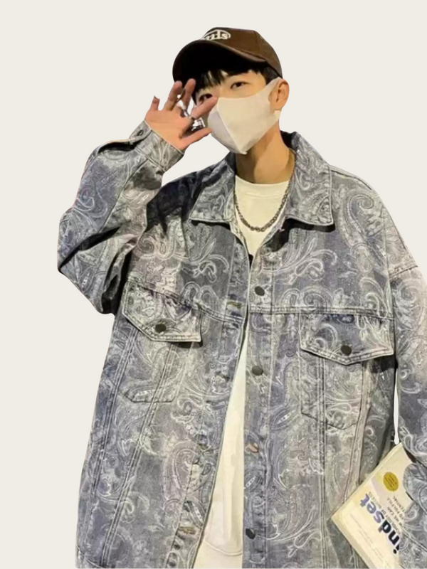 Person wearing a patterned denim jacket and cap on a plain background