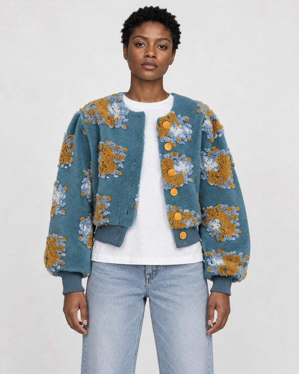 Model wearing the Women's Cropped Flower Jacket with Raised Patches and Gold Buttons in blue, front view