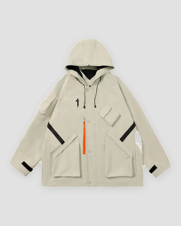 Beige hooded jacket with an orange zip pull, black chest straps, flap pockets and a small black logo, laid flat