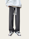 Person wearing gray sweatpants and a light gray hoodie on a beige background