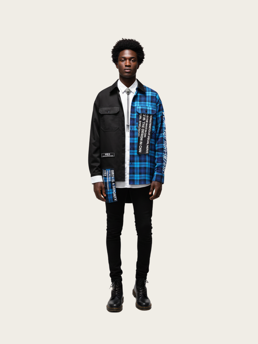 Person wearing a black and blue plaid shirt over a white shirt on a beige background