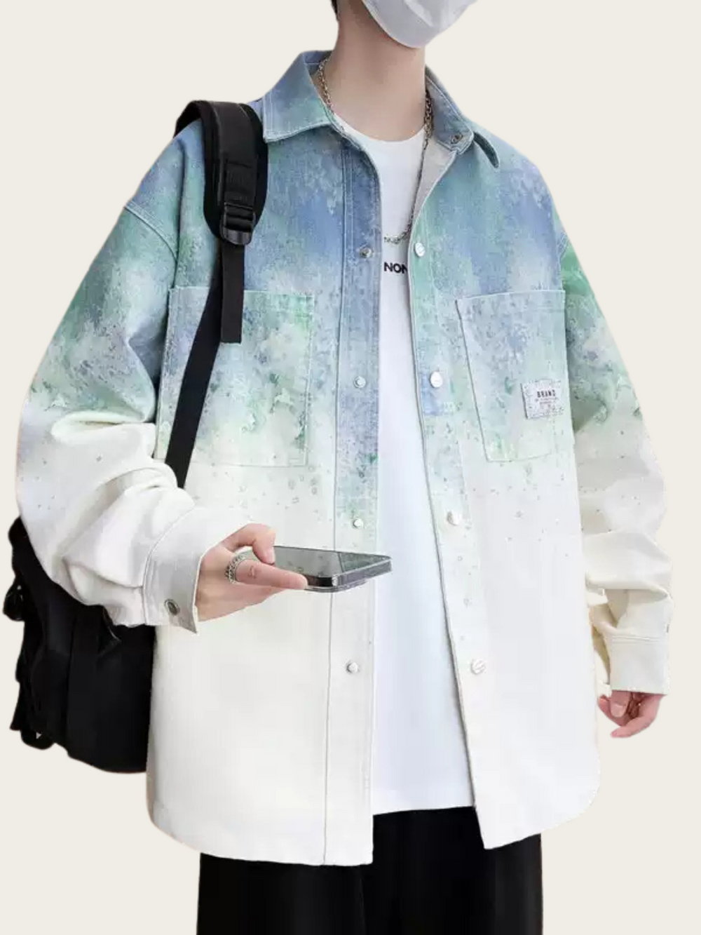 Person wearing a light blue and white gradient jacket holding a phone, with a plain background