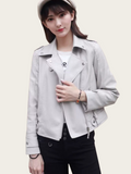 Woman wearing a light gray leather jacket on a plain background