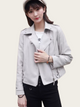 Woman wearing a light gray leather jacket on a plain background