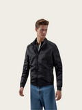 Man wearing a black jacket and blue jeans on a white background