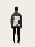 Person wearing a black denim jacket with colorful patchwork design on the back, standing against a white background.