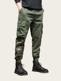Person wearing green cargo pants and black boots on a light background