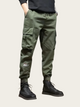 Person wearing green cargo pants and black boots on a light background