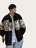 Person wearing a black jacket with floral embroidery on a plain background