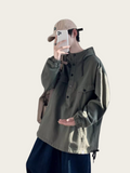 Person wearing a green jacket and dark pants, holding a phone with a beige cap.
