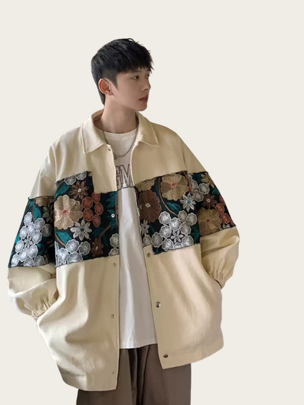 Person wearing a beige jacket with floral patchwork on a plain background