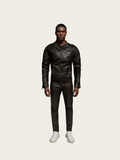 Person wearing a black leather jacket and pants on a light gray background