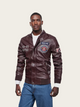 Man wearing a brown leather jacket with patches on a beige background