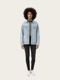 Person wearing a light blue denim jacket over a striped shirt on a white background