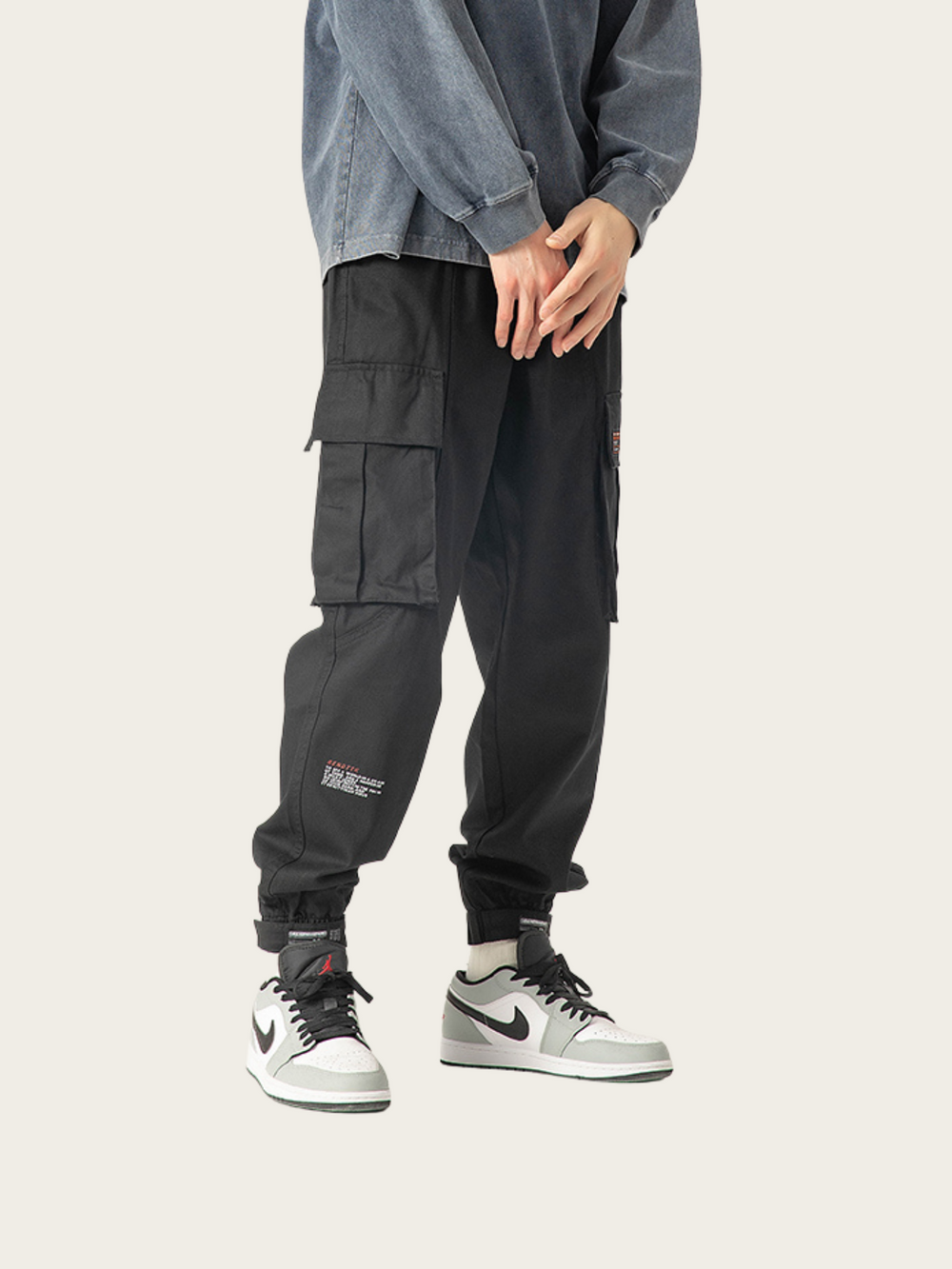 Person wearing dark cargo pants and Nike sneakers on a white background