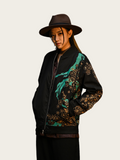 Person wearing a black jacket with floral patterns and a brown hat on a white background
