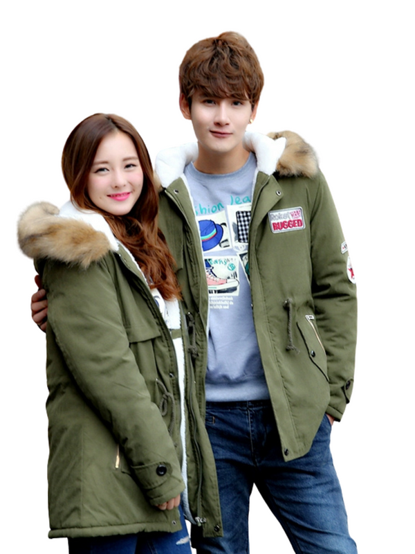 Two people wearing green parkas with fur-lined hoods on a white background