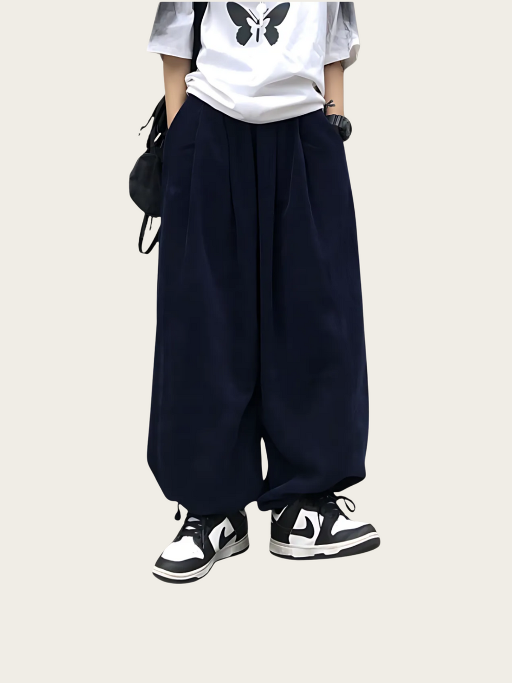 Person wearing navy wide-leg pants with a white shirt and black shoes on a white background