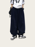 Person wearing navy wide-leg pants with a white shirt and black shoes on a white background
