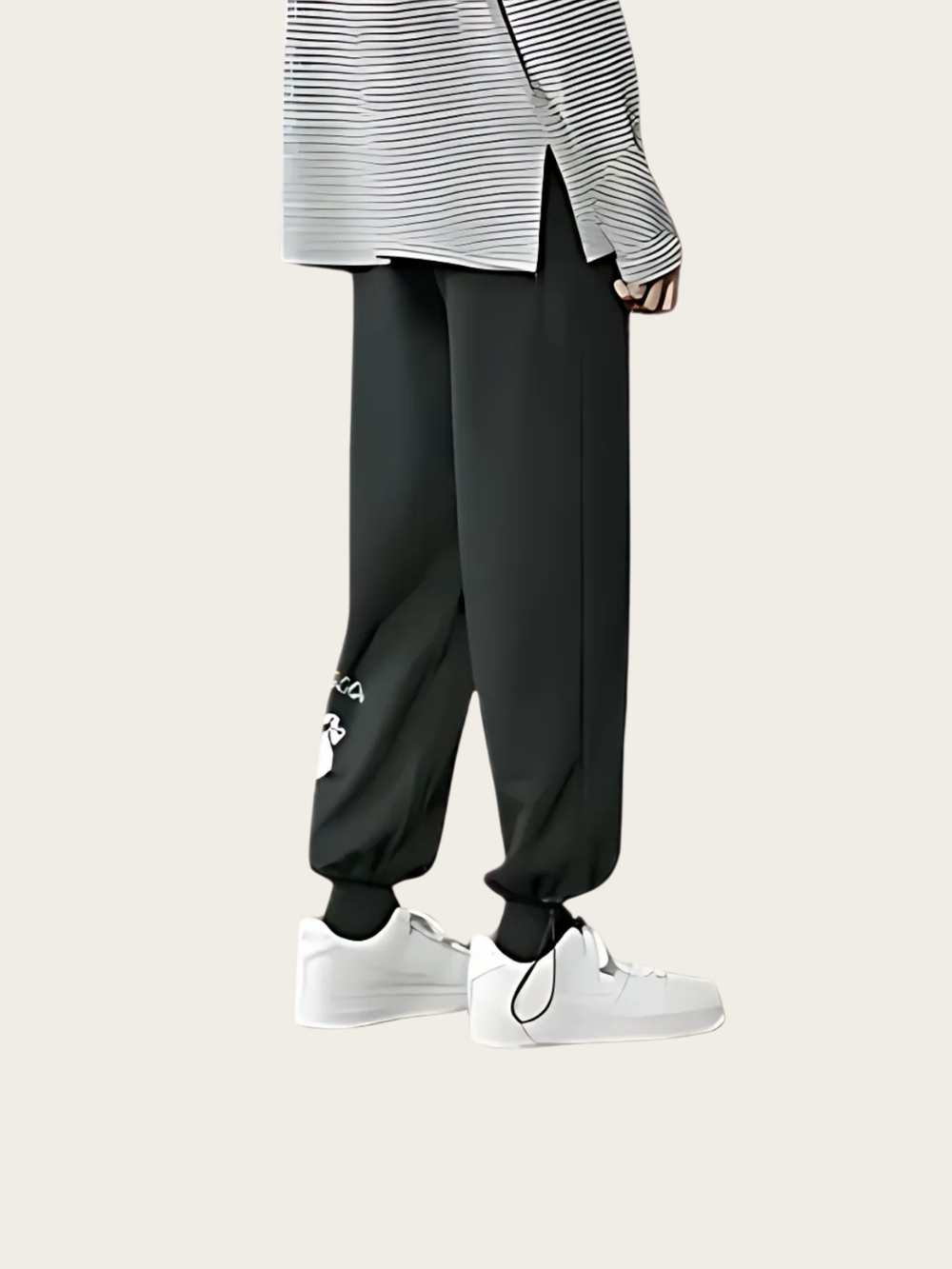 Person wearing black pants with a white logo and white sneakers on a light gray background