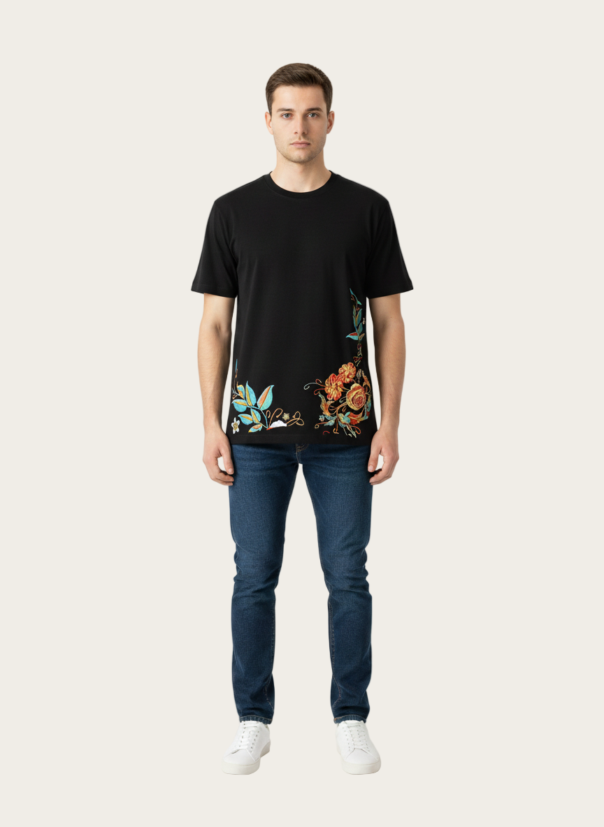 Man wearing a black t-shirt with colorful floral design and blue jeans on a white background