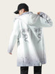 Person wearing a white coat with dragon designs on a plain background