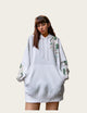 Person wearing a white hoodie and skirt with floral designs indoors.