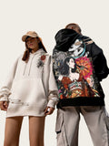 Two people wearing hoodies with artistic designs in an industrial setting