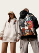 Two people wearing hoodies with artistic designs in an industrial setting