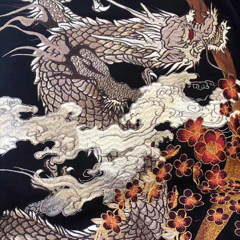 Embroidered dragon design on fabric with floral elements