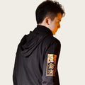 Person wearing a black hoodie with a tiger emblem on an orange background