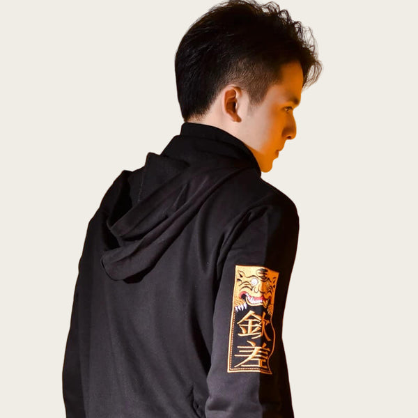 Person wearing a black hoodie with a tiger emblem on an orange background