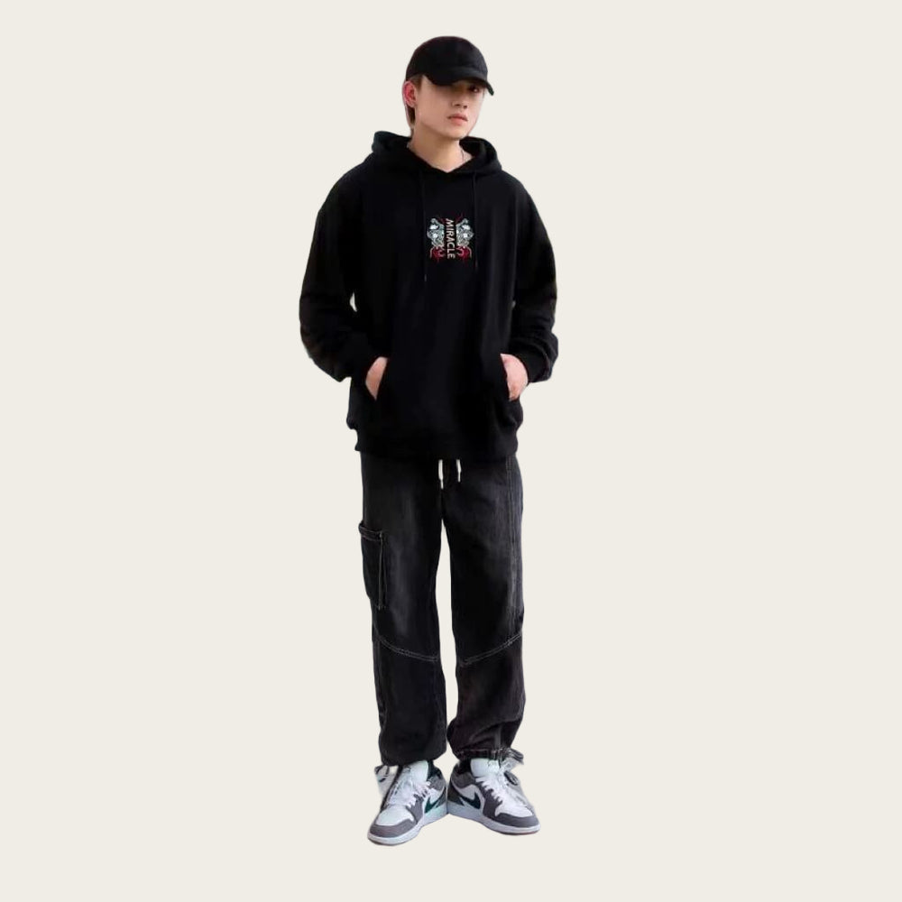 Person wearing a black hoodie and pants standing in front of red pillars.