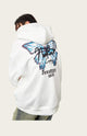 Person wearing a white hoodie with a butterfly design on the back, standing in an outdoor setting.