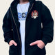 Person wearing a black hoodie with a logo and a white t-shirt with text.