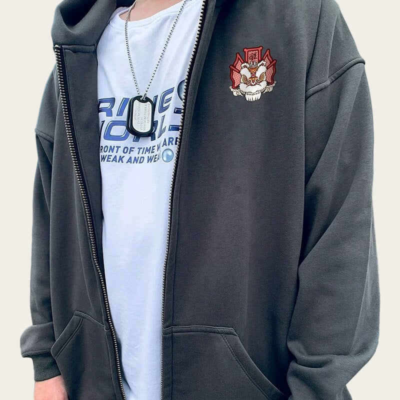 Person wearing a dark gray hoodie with a logo and a white t-shirt with text.