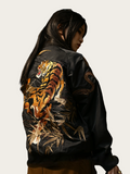 Black leather jacket with a tiger design on the back, worn by a person.