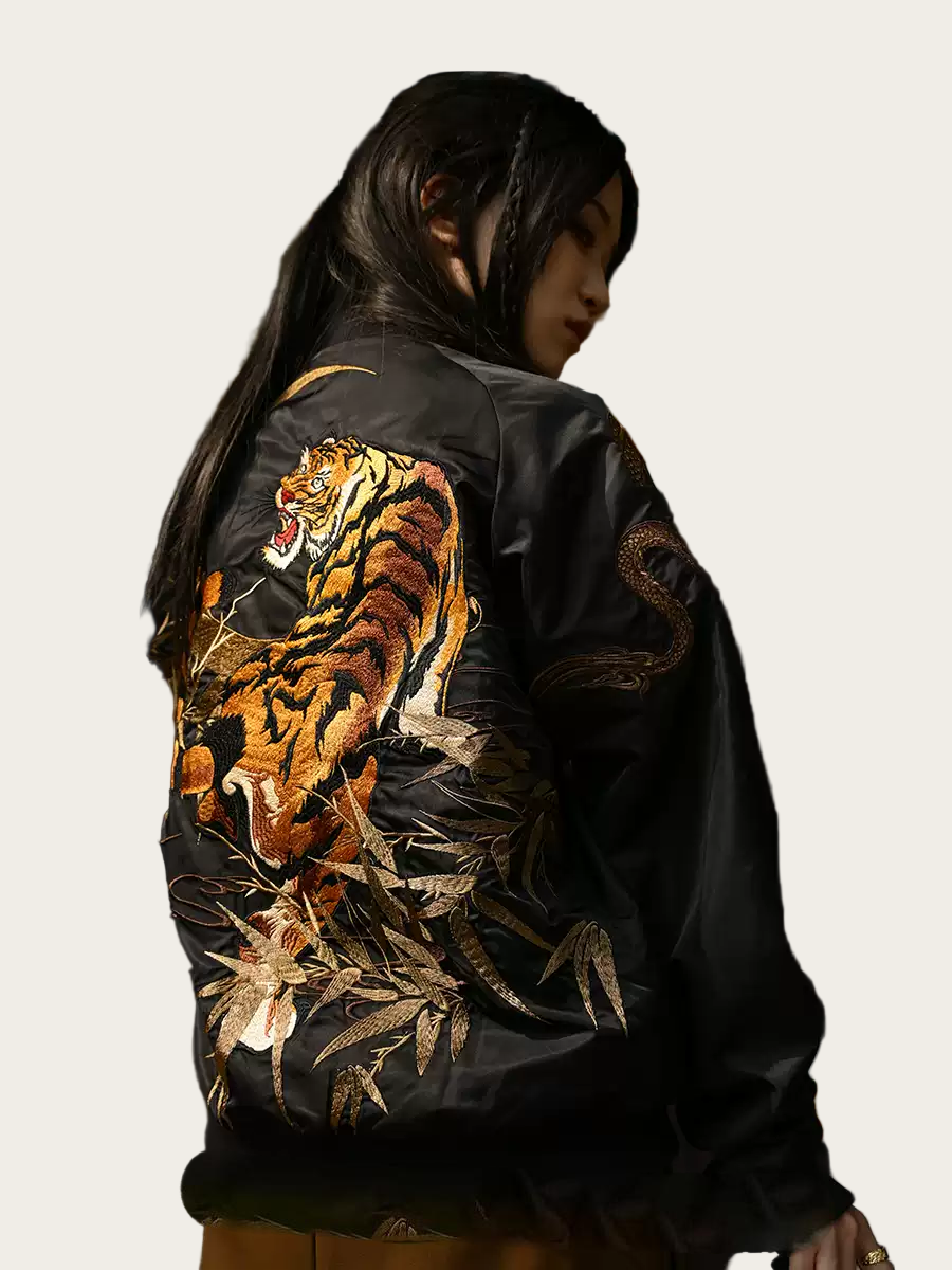 Black bomber jacket with a tiger design on the back, worn by a person.