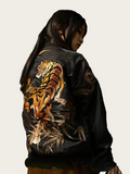 Black bomber jacket with a tiger design on the back, worn by a person.