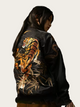 Black bomber jacket with a tiger design on the back, worn by a person.