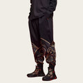 Person wearing black pants with intricate designs and black boots
