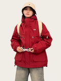 Person wearing a red jacket and beige cap indoors
