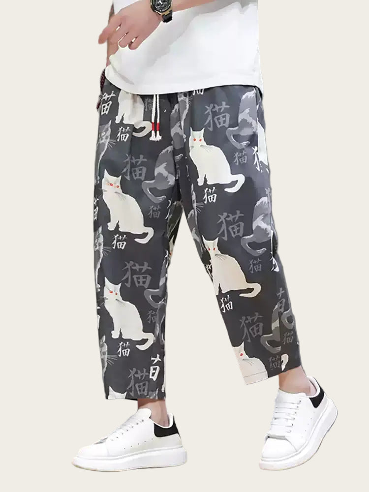Person wearing black pants with white cat print and white sneakers on a yellow background