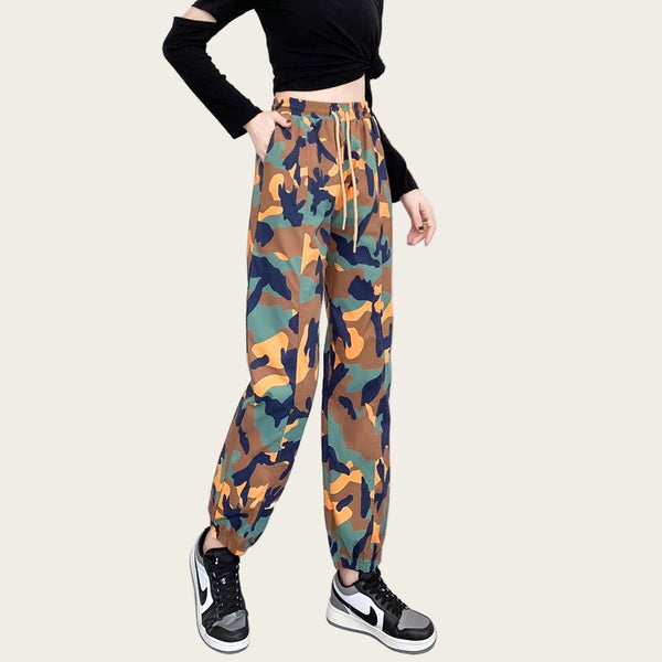Camouflage pants worn by a person with a black top and sneakers on a yellow background