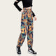 Camouflage pants worn by a person with a black top and sneakers on a yellow background