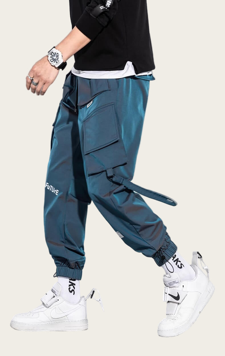 Person wearing teal cargo pants with visible branding, white sneakers, and a black top on a yellow background.