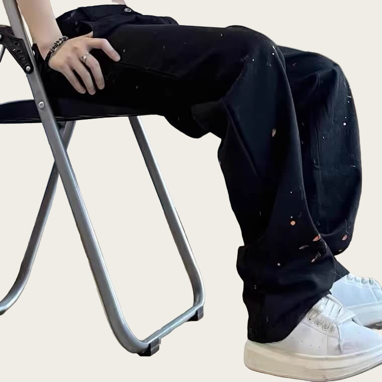 Person wearing black pants with white specks and white sneakers